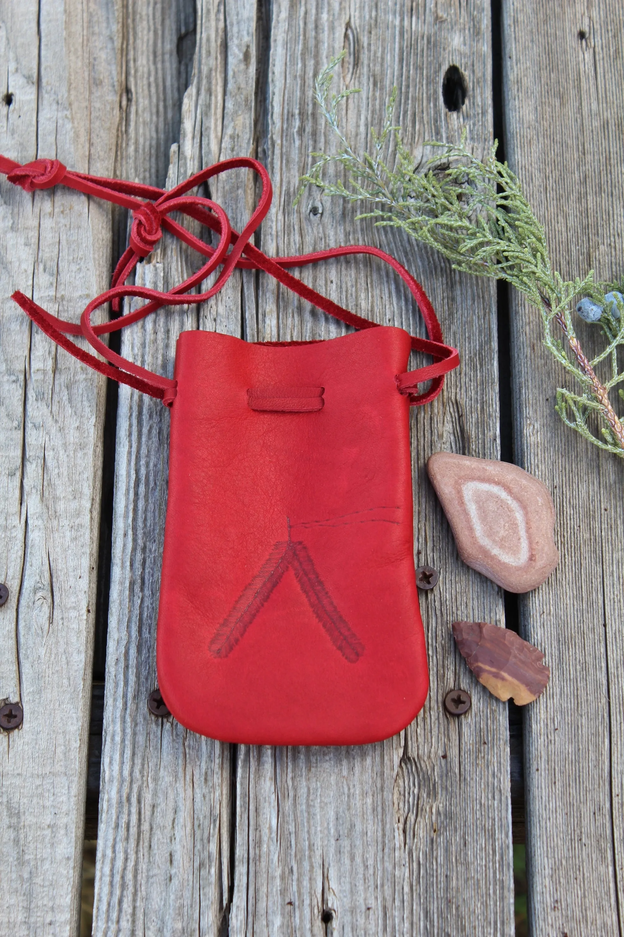 Red leather medicine bag with burned feathers